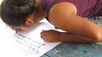 Close-up of woman leaning over to write on flip chart at a coffee pruning lecture, El Plátano, Panama